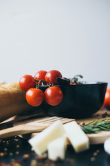 Tasty fresh tomatoes in a stylis black dish with delicious bread lying on wooden cutting board...