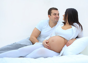 husband and pregnant wife lying on the bed in the bedroom.