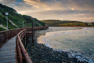 Wooden boardwalk leading to the beach under stormy skies at Gonubie, near East London, South Africa.