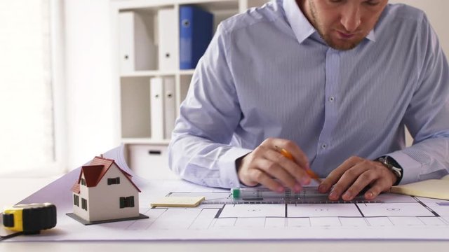 male architect with ruler measuring blueprint
