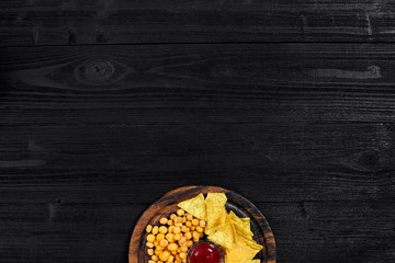 Obraz na płótnie Canvas Overhead view of snacks with sauce on black wooden table.