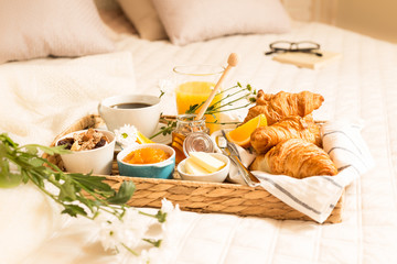 Continental breakfast on bed in elegant bedroom interior