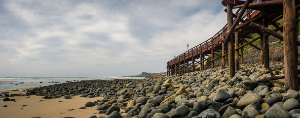 Wooden boardwalk above a rocky beach under stormy skies at Gonubie, near East London, South Africa.