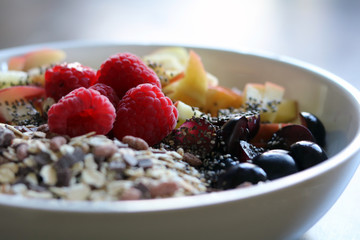 mixed fruit and cereal in a white bowl on brown wooden table