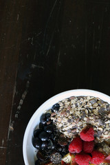 mixed fruit and cereal in a white bowl on brown wooden table