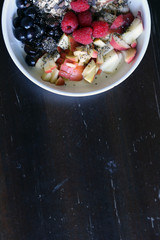 mixed fruit and cereal in a white bowl on brown wooden table
