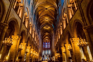 mystical image of the interior of Notre Dame cathedral In Paris with candles of lit faithful illuminated by colored stained glass windows - obrazy, fototapety, plakaty