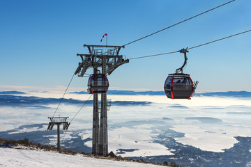 Gondola lift. Cabin of ski-lift in the ski resort in the early morning at dawn with mountain peak in the distance. Winter snowboard and skiing concept © bychykhin