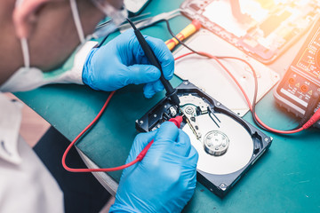The abstract image of the technician repairing inside of hard disk drive by multimeter. the concept...