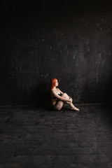 Fototapeta na wymiar Long legs girl, woman sit on floor in black lingerie in tattoo on black background