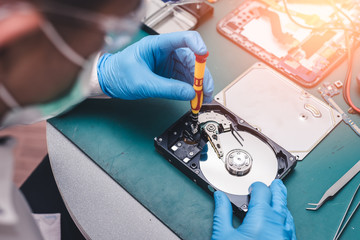 The abstract image of the technician repairing inside of hard disk drive by screwdriver in the lab. the concept of data, hardware, technician and technology. - obrazy, fototapety, plakaty