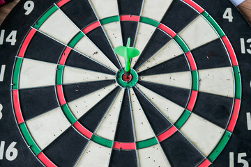 Green dart arrow hitting in the target center of dartboard
