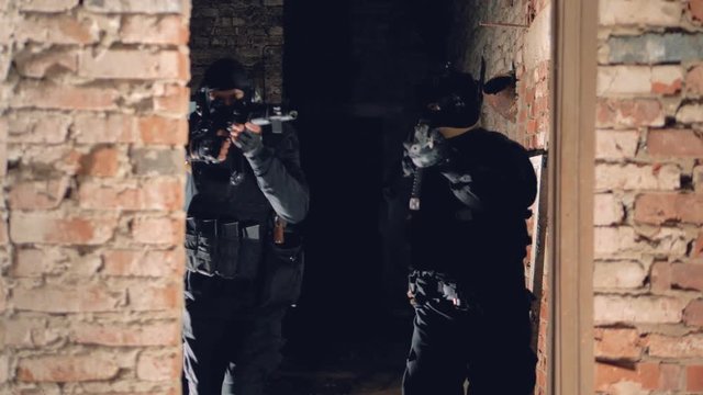 Two snipers in black slowly move inside an ancient building during hostages rescuing operation. 4K.
