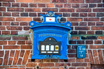 Post box of blue painted metal on red brick wall