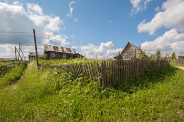 north Russian village Isady. Summer day, Emca river, old cottages on the shore, old wooden bridge. Abandoned building.