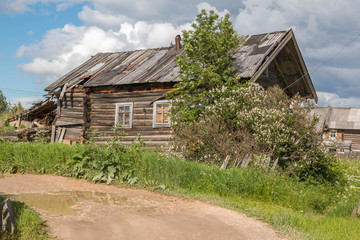 Fototapeta na wymiar north Russian village Isady. Summer day, Emca river, old cottages on the shore, old wooden bridge. Abandoned building.