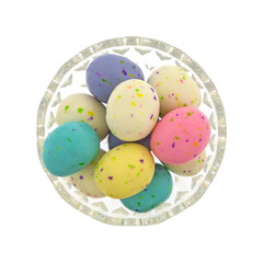 Top view of several speckled Easter egg malt ball candies in a glass bowl isolated on a white background.