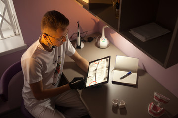 Dental doctor looks x-ray on tablet computer in dental office.