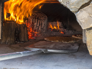 Cooking with firewood in an outdoor countryside oven. The flames burn the olive tree. In the...