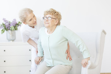 Young caregiver assisting smiling elderly