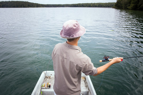 A man is fly fishing from boat on a lake.