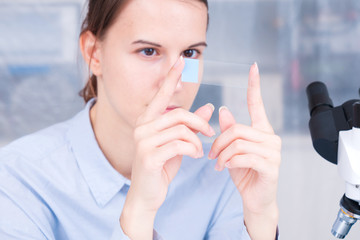 student girl with glass empty microscope slide in hand