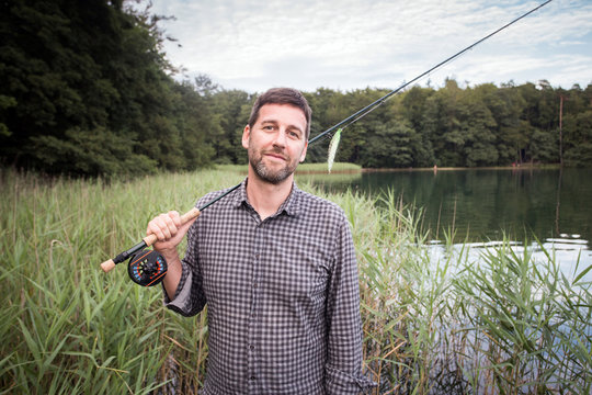 Caucasian fly fisher with his fishing rod at a lake.
