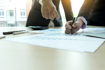 businessman and businesswoman working to analyses market  chart on wood table in