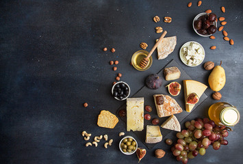 Food background with cheese. Blocks of moldy cheese, grapes, figs, honey, pear, dates, pickled...