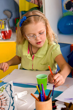 Small students painting in art school class. Child drawing by paints on table. Kid on balloons background. Top view of girl in kindergarten. She does not want to draw with others. Spring drawings.