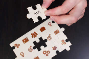 The concept of business, technology, the Internet and the network. A young businessman collects a puzzle with the proper inscription: ADS