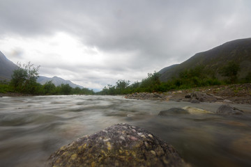 Clouds above the mountains and river. Long exposure