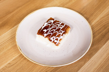 Coconut cake on ceramic plate. Wooden background. Delicious cake dessert served at the restaurant.