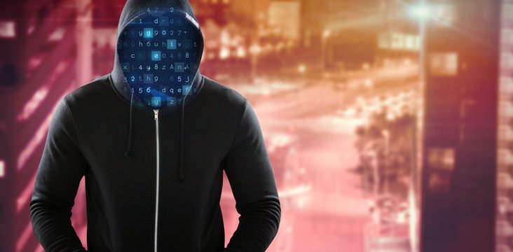 Composite image of male hacker in black hoodie standing