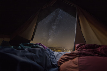 milky way view front inside a camping tent, with a couple sleeping inside