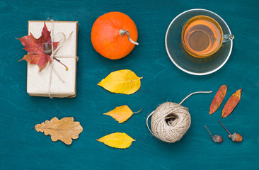 Autumn flat lay with pumpkins,  a cop of coffee, fall leaves and a gift. Thanksgiving holiday concept flat lay. Top view