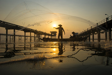 Fisherman is throwing a net to catch fish at the reservoir in the morning.