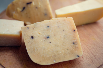 Cheese with spices and cloves served on wooden table. Traditional pieces of french and italy hand-made food