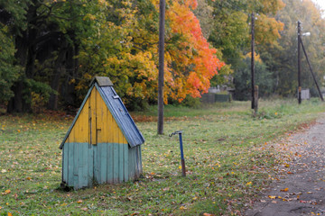 well in the village on the street in autumn.