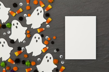 Halloween background with ghosts and candy corn on a slate background