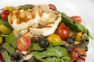 Grilled Halloumi Cheese poured with garlic olive oil salad witch grilled eggplant, cherry tomatoes, black olives and spinach. healthy food. Close up
