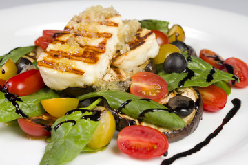 Grilled Halloumi Cheese poured with garlic olive oil salad witch grilled eggplant, cherry tomatoes, black olives and spinach. healthy food. Close up