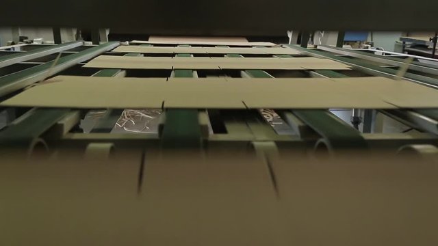 Manufacture of cardboard boxes. Cardboard manufacturing layering rollers roll industrial industry printing packaging material closeup. Paper corrugated box factory. Footage with sound.