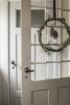 A Christmas wreath with pinecones on a door in a house