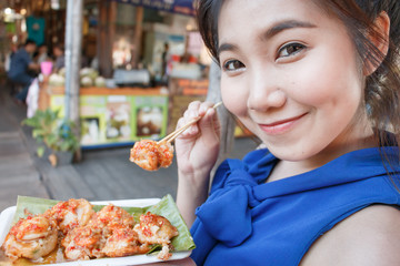 Cute girl of asian happy to eat Mini Fried Mussels in floating market