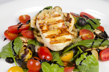 Grilled Halloumi Cheese poured with garlic olive oil salad witch grilled eggplant, cherry tomatoes, black olives and spinach. healthy food. Close up