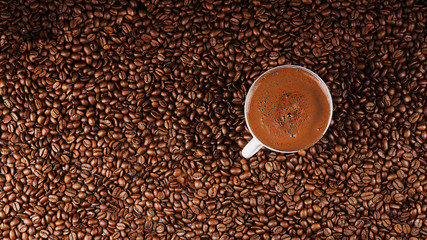    Coffee cup on coffee beans in close up photo.