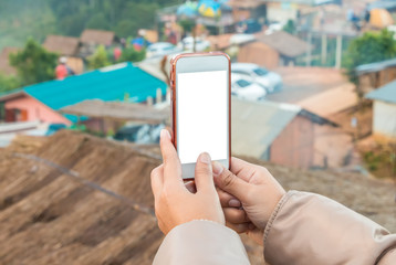 Hand holding cell phone to take a photo view of city on the mountain , blank screen on white