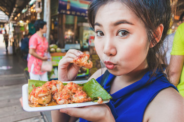 Cute girl of asian happy to eat Mini Fried Mussels in floating market