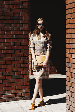 Blonde girl posing against brick walls